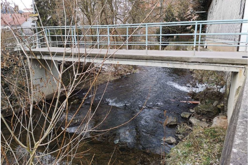 Sanierungsbedürftige Fußgängerbrücke über einen kleinen Fluss