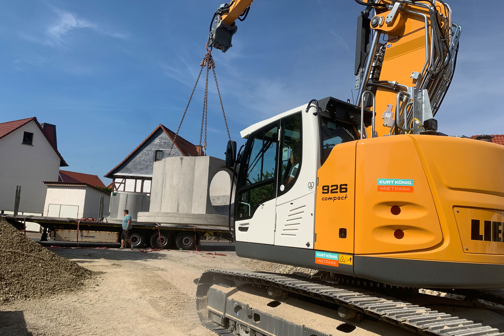 Gelbes Baufahrzeug transportiert großes rundes Betonteil auf der Baustelle