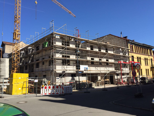 Eingerüstetes Mehrfamilienhaus an einer innerstädtischen Straße